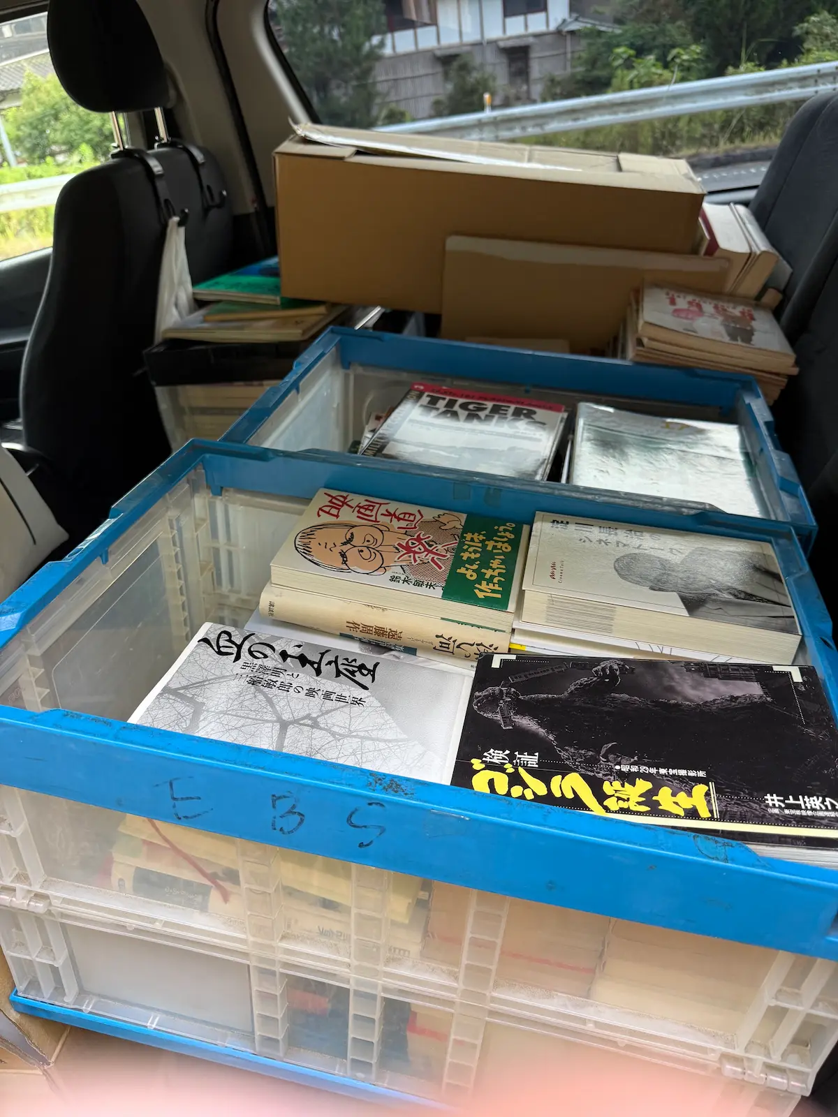 広島市安芸区でお預かりした映画関係4箱・ミリタリー関係2箱のうち、ハイエースの車内に積み込んだオリコン（折りたたみコンテナ）2台と段ボール。手前のオリコンには井上英之『検証 ゴジラ誕生 昭和29年東宝撮影所』・鈴木敏夫『映画道楽』・『淀川長治のシネマトーク』・『映画監督 溝口健二』が、奥のオリコンには『TIGER TANKS』の表紙が見えている