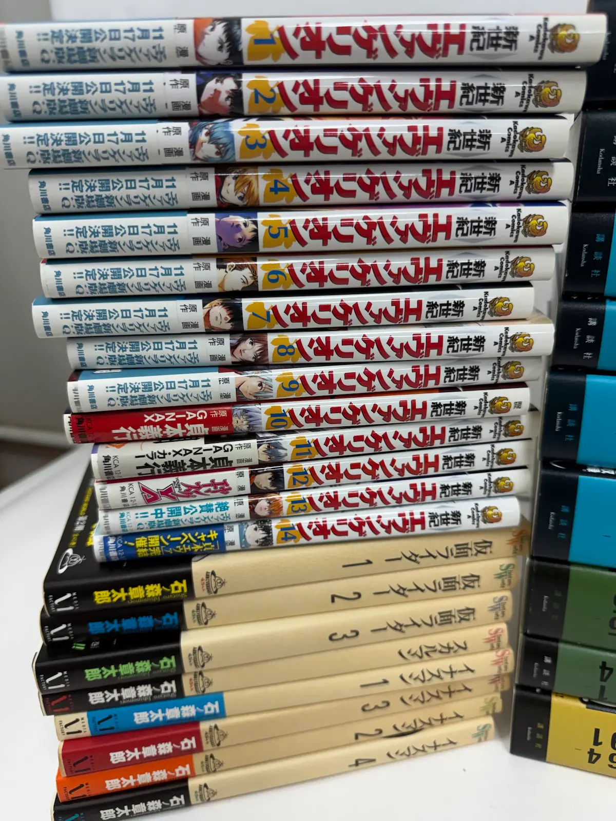 貞本義行『新世紀エヴァンゲリオン』全14巻（角川コミックス・エース）と、石ノ森章太郎『仮面ライダー』1〜3巻・『イナズマン』1〜4巻・『スカルマン』1冊（いずれも小学館）が並んでいる様子