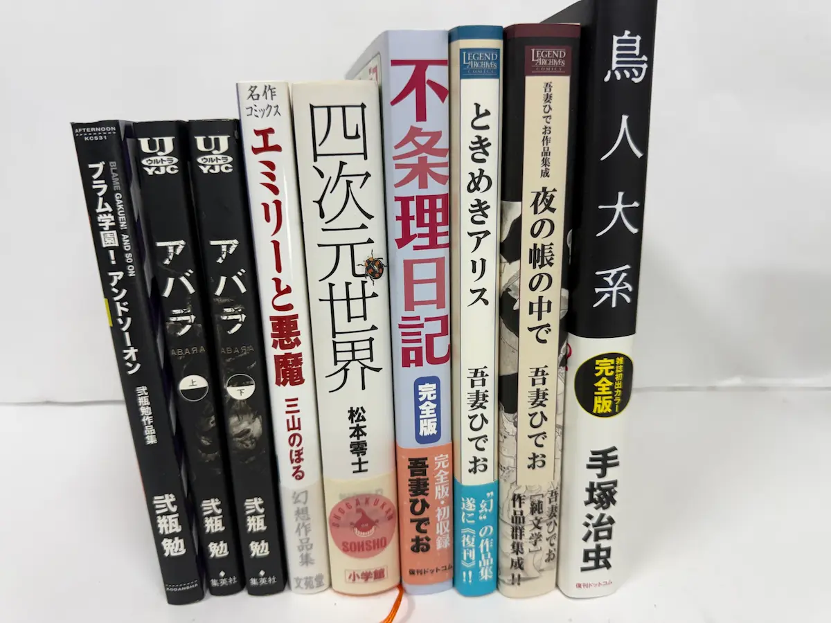 広島市東区の遺品整理買取でお譲りいただいた本の背表紙9冊——弐瓶勉『ブラム学園！アンドソーオン』（講談社AFTERNOON KC）、『アバラ』上下（集英社UJ ULTRA YJC）、三山のぼる『エミリーと悪魔』（名作コミックス幻想作品集）、松本零士『四次元世界』（小学館）、吾妻ひでお『不条理日記 完全版』『ときめきアリス』『夜の帳の中で 吾妻ひでお作品集成』（復刊ドットコム LEGEND ARCHIVES）、手塚治虫『鳥人大系 雑誌初出カラー完全版』（復刊ドットコム）