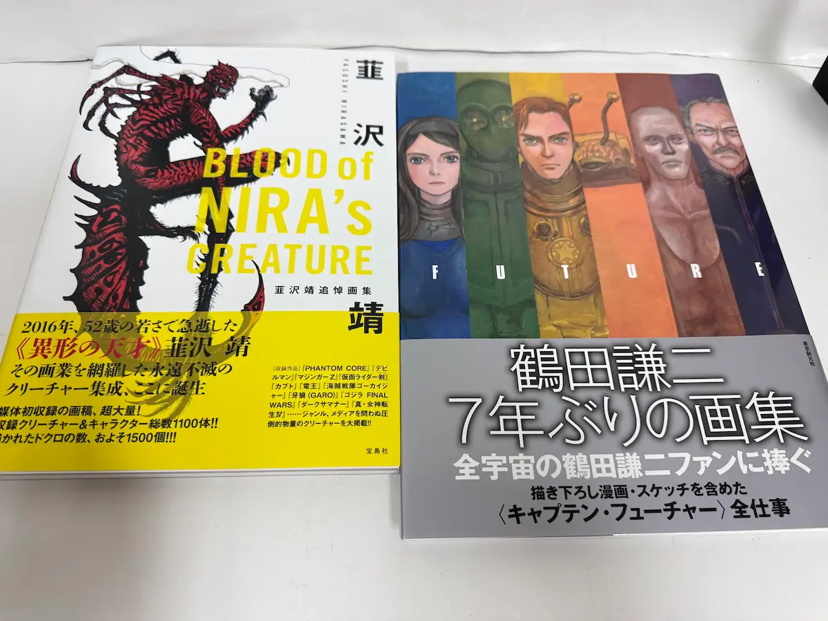 韮沢靖『BLOOD of NIRA'S CREATURE』追悼画集（宝島社）と鶴田謙二『FUTURE』（東京創元社）の表紙アップ。左は黄色い帯に「2016年、52歳の若さで急逝した《異形の天才》韮沢 靖」の文字、赤いクリーチャーのイラスト。右は「鶴田謙二 7年ぶりの画集」「全宇宙の鶴田謙二ファンに捧ぐ」「〈キャプテン・フューチャー〉全仕事」のグレーの帯、キャラクターたちが縦に並んだ表紙