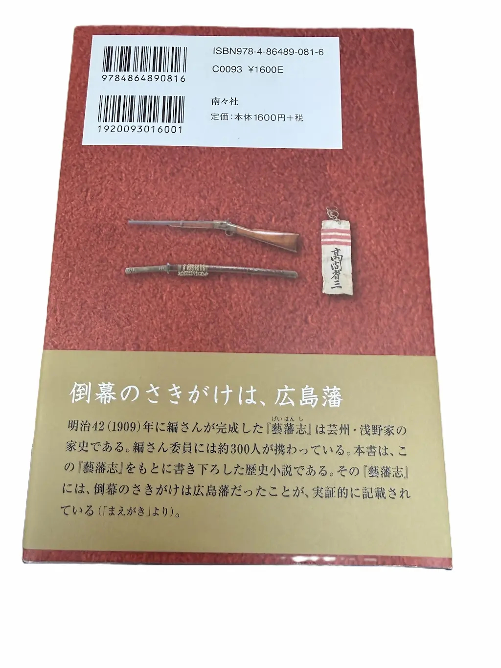 穂高健一『広島藩の志士』（南々社）の裏表紙。赤い地の上に、銃と刀、紅白の線が入った「高間省三」と書かれた札の写真。上にISBN 978-4-86489-081-6、南々社、定価本体1600円＋税。帯には「倒幕のさきがけは、広島藩」と、本書が浅野家の家史『藝藩志』をもとに書き下ろした歴史小説であることを記したまえがきの一節