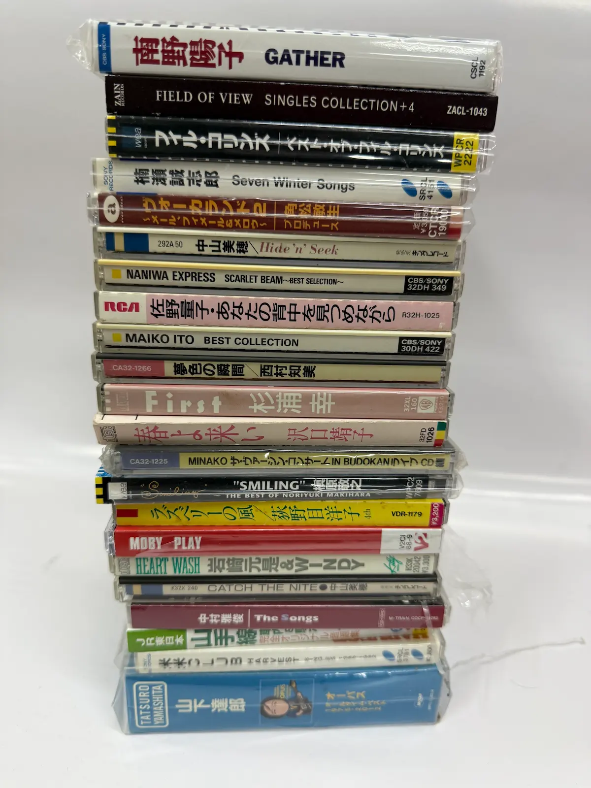 呉市内でお譲りいただいたCD22枚を縦に積み上げた背表紙。上から南野陽子GATHER、FIELD OF VIEW SINGLES COLLECTION+4、ベスト・オブ・フィル・コリンズ、楠瀬誠志郎 Seven Winter Songs、VOCALAND 2、中山美穂 Hide'n'Seek、NANIWA EXPRESS SCARLET BEAM、佐野量子、伊藤麻衣子、西村知美、杉浦幸 First、沢口靖子 春よ来い、本田美奈子、槇原敬之 SMILING、荻野目洋子 ラズベリーの風、MOBY PLAY、岩崎元是&WINDY HEART WASH、中山美穂 CATCH THE NITE、中森明菜 The Songs、JR東日本 山手線自動放送音源集、米米CLUB、山下達郎 OPUS が並ぶ