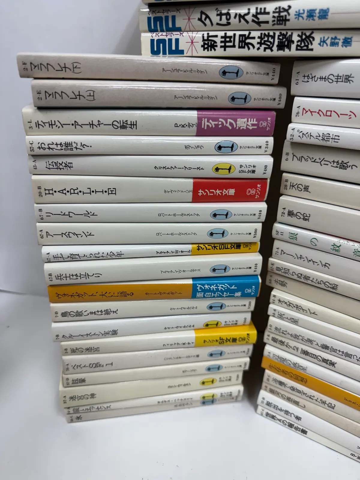 サンリオSF文庫の背表紙の接写。背表紙左端に「2-F」「2-E」「3-L」「57-C」「43-A」といった背番号が印刷されており、下部に丸いマークと「サンリオSF文庫」の表記がある
