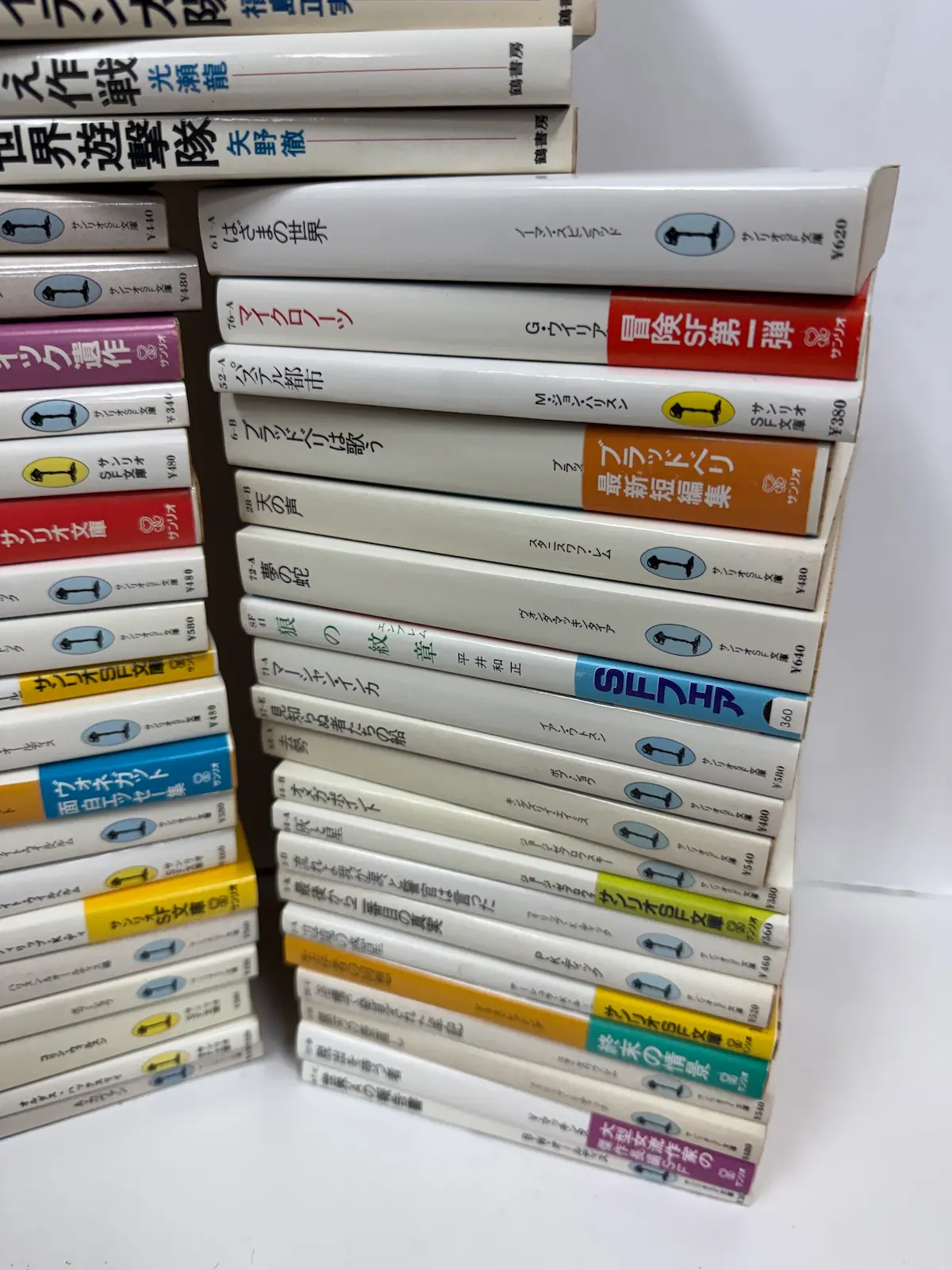 サンリオSF文庫の背表紙の接写・下部。「61-A はざまの世界」「52-A パステル都市」「72-A 夢の蛇」などの背番号と書名、定価が読み取れる。一部の本には帯が掛かったまま残っている