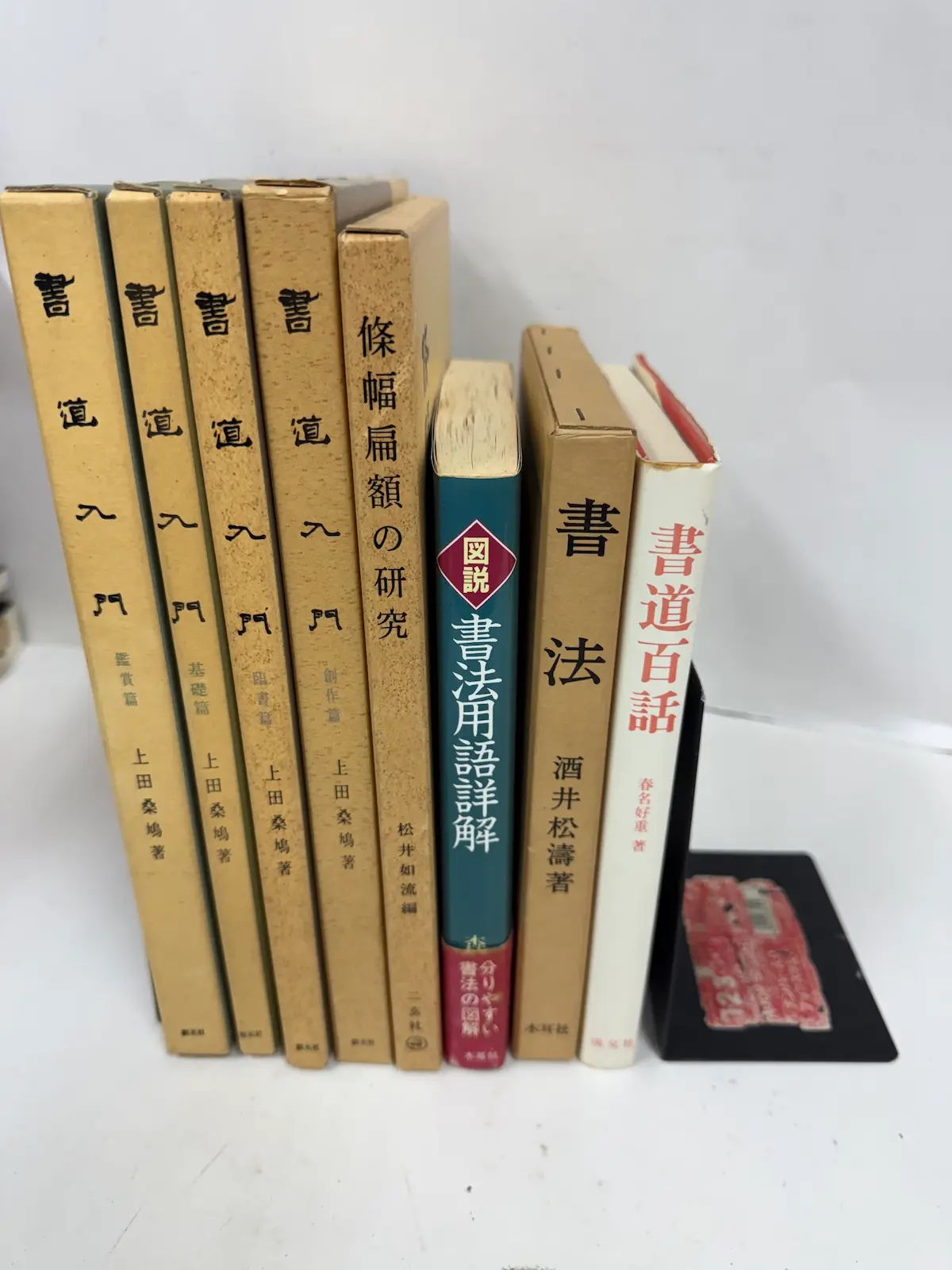呉市内でお譲りいただいた書道関係の入門書・研究書8冊を並べたところ。上田桑鳩『書道入門』の鑑賞篇・基礎篇・臨書篇・創作篇の4冊（創元社）、松井如流編『條幅扁額の研究』（二玄社）、『図説 書法用語詳解』（雄山閣）、酒井松濤『書法』（木耳社）、春名好重『書道百話』（淡交社）の背表紙と表紙が見えている