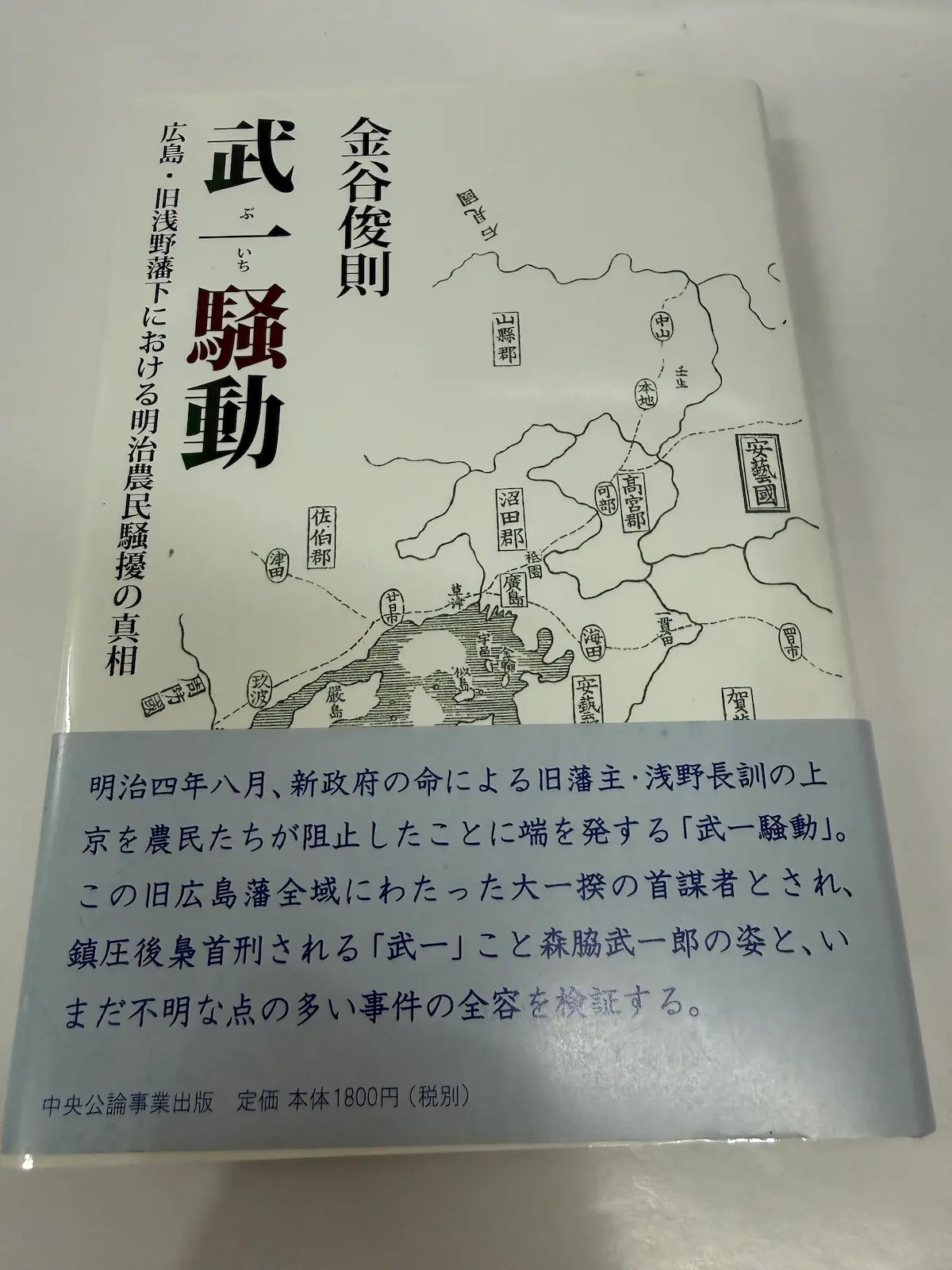 金谷俊則『武一騒動 広島・旧浅野藩下における明治農民騒擾の真相』（中央公論事業出版）の表紙と帯。表紙には安藝國・山縣郡・沼田郡・佐伯郡・高宮郡・海田・呉市などの旧郡名が入った広島の古地図が描かれ、青い帯に明治四年八月の浅野長訓の上京と武一こと森脇武一郎についての紹介文、定価本体1800円と記されている